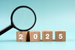 Magnifying glass and 2025 number engraved on wood block New Year concept