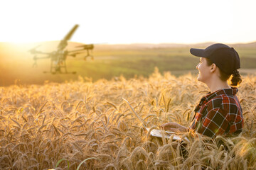Poster - Woman farmer controls drone sprayer with a tablet. Smart farming and precision agriculture.