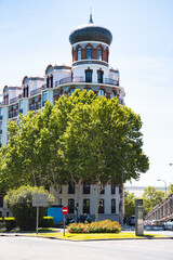 Wall Mural - A beautiful view of a church behind residential buldings and tree branches - Madrid, Spain
