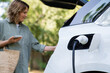Woman with shopping bag next to a charging electric car