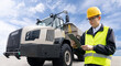 Man worker with tablet computer stands next to mining truck