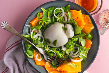 Burrata is a Pulian Italian cheese with a creamy base and a salad of red Sicilian oranges. Summer Italian cuisine, Puglia recipes, summer food. Summer lunch ideas, pink table
