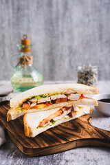 Poster - Appetizing sandwich with chicken breast, tomatoes, lettuce and sauce on a board vertical view