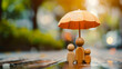 A wooden family under an umbrella.