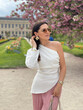 beautiful woman with dark hair in elegant clothes with accessories posing in spring garden with blossom sakura tree