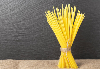 raw spaghetti pasta from durum wheat vertically on a dark background