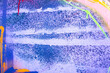 Messy paint strokes and smudges on an old painted wall. Pink, purple, white, yellow color drips, flows, streaks of paint and paint sprays on purple wall background