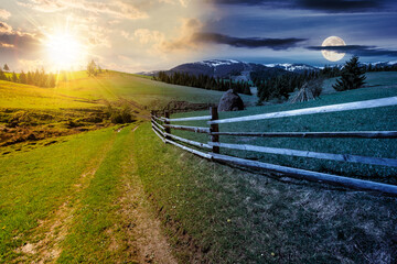 Wall Mural - rural landscape in mountains on spring equinox. wooden fence along the path through grassy fields on