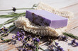 Lavender soap with flowers lying on a washcloth on a vintage wooden board. Organic natural product.