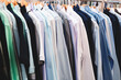 A rack of clothes with a variety of colors and styles. The clothes are hanging on a rack, and the colors include blue, green, and white