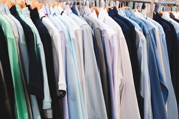 Wall Mural - A rack of clothes with a variety of colors and styles. The clothes are hanging on a rack, and the colors include blue, green, and white