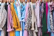 A rack of clothes with a variety of colors and patterns. The clothes are hanging on a clothesline, and the overall mood of the image is cheerful and colorful