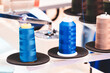 Three spools of thread are displayed on a table. The blue spool is the tallest and the other two are shorter