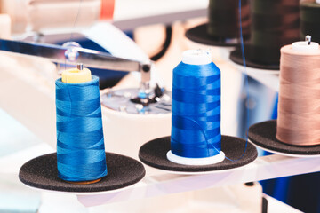 Aufkleber - Three spools of thread are displayed on a table. The blue spool is the tallest and the other two are shorter