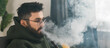 © satura_ - Banner bearded millennial or gen z man smoking hookah while relaxing on sofa at home copy space - chill time and resting concept