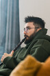 © satura_ - Portrait bearded man is smoking hookah at home and blowing cloud of smoke, copy space and place for text - chill time and resting concept