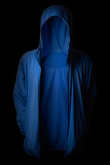 A person wearing a hoodie standing in the dark