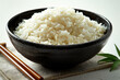 Rice in a bowl and chopsticks on a white background.