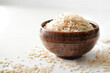 Bowl with raw rice on white wooden table, closeup view