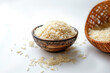 Raw uncooked long rice in a bowl and bamboo basket on white background