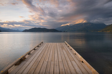 Wall Mural - Wooden boat dock leading out to a lake with calm waters with a sunset sky. Harrison Lake, east of the lake are the Lillooet Ranges while to the west are the Douglas Ranges, British Columbia, Canada. 