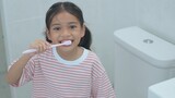Fototapeta  - A young girl is brushing her teeth in a bathroom