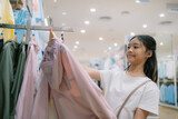 Fototapeta  - A young girl is shopping for clothes in a store