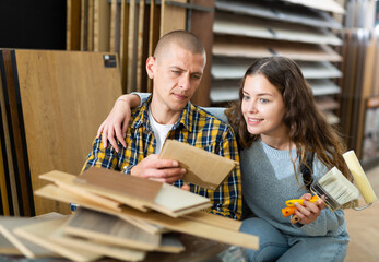 Wall Mural - Modern family couple standing together with sample of laminated flooring in building store