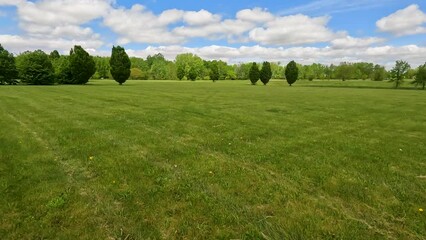 Sticker - Beautiful summer or springtime scene walking through an open grassy green field that has been freshly mowed. Leafy green trees in the distance. Perfect cloudy blue sky above.