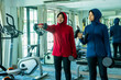 Muslim sport, Happy cheerful Asian Muslim mother and daughter Wearing Hijab and Sportswear smiling while preparing for a workout with weights at the gym, Muslim sport concept.