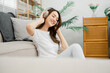© Satori Studio - Joyful woman with closed eyes feeling the music through her headphones, sitting on a couch at home.