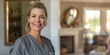 © Duka Mer - A beautiful, confident woman in her mid40s with blonde hair tied back and blue eyes standing inside of an elegant home, smiling at the camera.