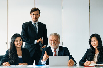 Wall Mural - Senior caucasian manager working in office with assistance of young Asian business people and translator in meeting. Corporate international business and secretary language translation concept. uds