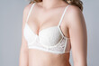 Blonde woman in white push up bra on gray background, decollete area care