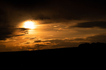 Wall Mural - Orange sunset with dramatic clouds.