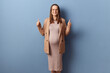 Satisfied beautiful young adult pregnant woman wearing dress and jacket posing isolated over blue background showing thumbs up approved something smiling to camera