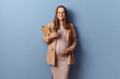Pretty young adult pregnant businesswoman wearing dress and jacket posing isolated over blue background working with papers holding clipboard and cup of disposable coffee