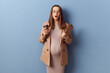 Shocked young adult pregnant woman wearing dress and jacket posing isolated over blue background holding papers and takeaway coffee looking at camera with shocked face