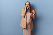 Shocked despair young adult pregnant woman wearing dress and jacket posing isolated over blue background screaming with irritated face holding cup of takeaway coffee
