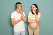 Smiling delighted young married pregnant family standing isolated over light green background man and woman in casual clothing looking at each other with smile holding chins
