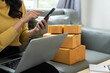 © MrAshi - Small business startup, SME owner, female entrepreneur working on receipt boxes and checking online orders, laptop to prepare to pack boxes to sell to customers. Close-up photo