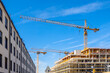 © Westend61 - Germany, Bavaria, Munich, Industrial cranes looming over construction site