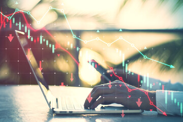 Wall Mural - Side view of male hands using laptop and smartphone with falling red forex chart and map on blurry outdoor background. Trade and crisis concept. Double exposure.