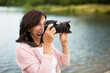 Portrait of beautiful mature woman on vacation, taking photos with professional camera, capturing beauty in nature around her.