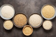 Various varieties of raw dry rice in bowls on a dark background. View from above.