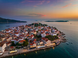 Fototapeta Londyn - Primosten, Croatia - Aerial view of Primosten peninsula and old town on a sunny summer morning in Dalmatia, Croatia. Blue and golden sky at sunrise on the Adriatic sea coast