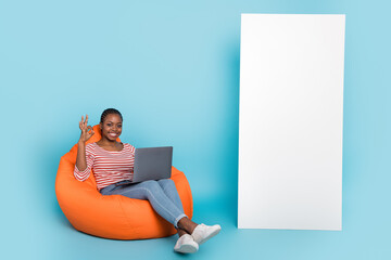 Wall Mural - Full body portrait of positive attractive girl sit bag use netbook show okey symbol empty space panel isolated on blue color background