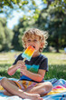 Young boy smiling with giant rainbow popsicle in the park