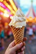 Hand holding vanilla ice cream cone with colorful bokeh background