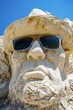 Detailed sand sculpture with sunglasses under clear blue sky